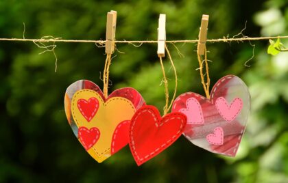 Multicolored paper hearts clipped to a string with clothespins